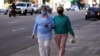 Dos mujeres usando mascarillas para prevenir la diseminación del coronavirus caminan del brazo por una calle del centro de Montevideo, Uruguay, el 19 de mayo de 2020.