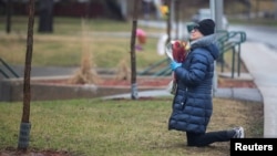 A woman prays as she leaves flowers outside Residence Herron, a senior's long-term care facility, following a number of deaths since the coronavirus disease (COVID-19) outbreak, in the suburb of Dorval in Montreal Quebec, Canada April 13, 2020.