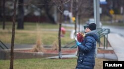 Une femme prie en laissant des fleurs à l'extérieur de la résidence Herron, un établissement de soins pou personnes âgées, après plusieurs pendant l'épidémie de COVID-19, dans la banlieue de Dorval à Montréal, Québec, Canada, le 13 avril 2020. (Photo: REUTERS / Christinne Muschi)