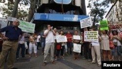 Demonstrators hold signs as they protest against what they say is abuse of the system by banks and the failure of the government to stop them, in front of the headquarters of Spain's center-right People's Party [Partido Popular] in Madrid, July 8, 2012.