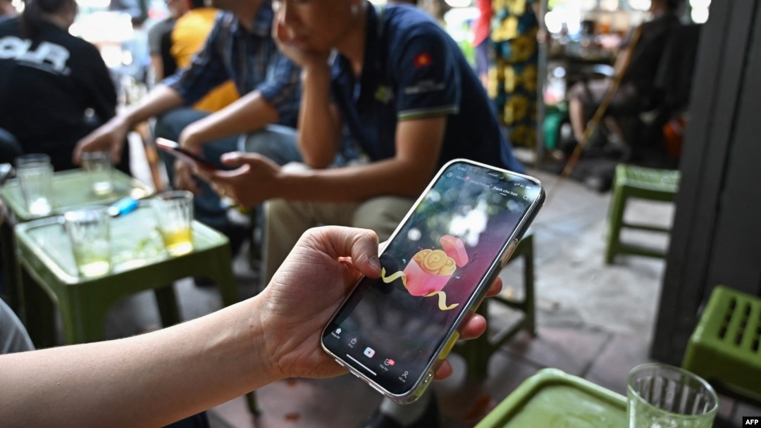 FILE - A man looks at the social media platform TikTok on his smartphone in Hanoi, Vietnam, Oct. 6, 2023. New internet rules requiring Facebook and TikTok to verify user identities and hand over data to authorities came into force on Dec. 25, 2024.