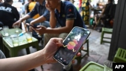 FILE - A man looks at the social media platform TikTok on his smartphone in Hanoi, Vietnam, Oct. 6, 2023. New internet rules requiring Facebook and TikTok to verify user identities and hand over data to authorities came into force on Dec. 25, 2024.