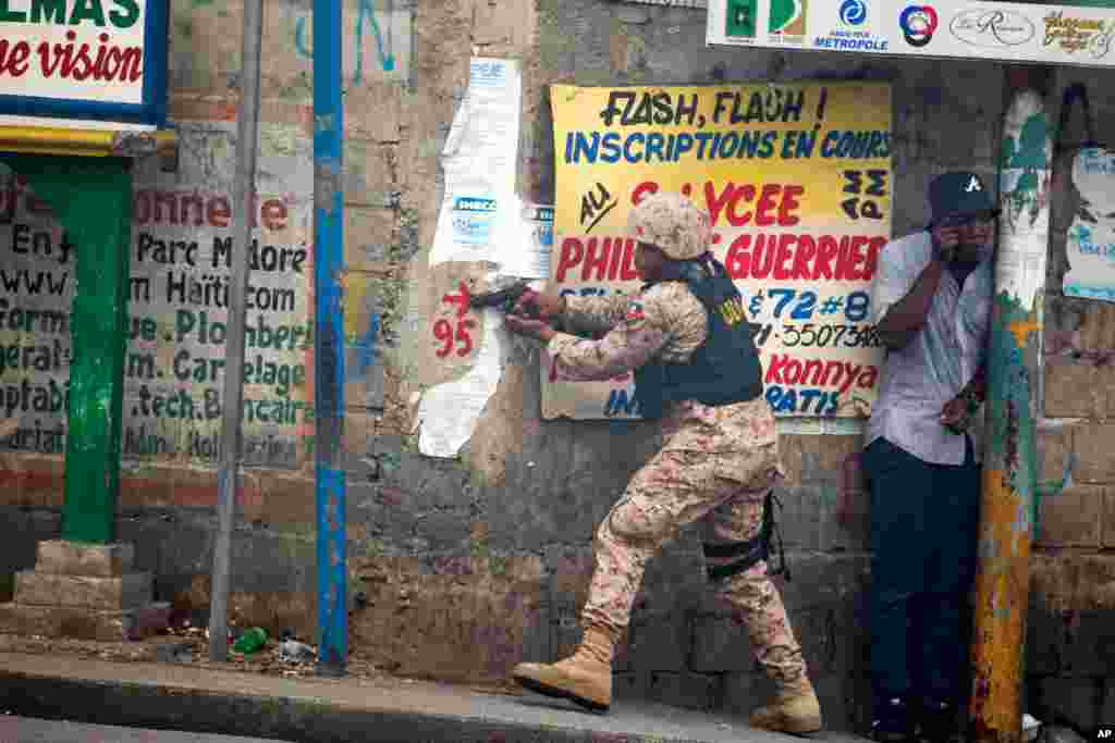 A police officer points his gun at residents of the Delmas 95 district during a protest demanding the resignation of Haiti President Jovenel Moise in Port-au-Prince, Haiti, Nov. 18, 2019.
