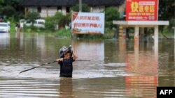 Seorang pria berjuang mengarungi banjir yang menggenangi jalan di Rongan, Wilayah Guangxi di selatan China setelah hujan lebat melanda wilayah itu, 9 Juni 2019. (Foto: AFP)