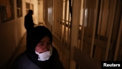 (FILE) A woman looks for a family member who was a detainee in Sednaya prison walks through cells, in Sednaya, Syria, December 17, 2024.