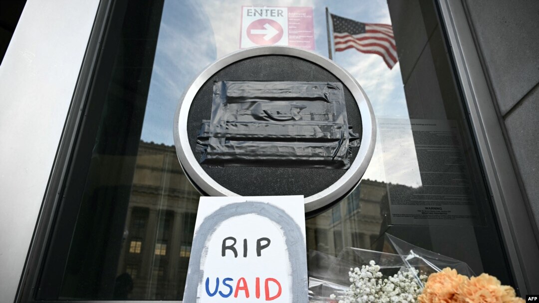 Sejumlah tanda penghormatan diletakkan di bawah logo USAID yang telah disegel di markas lembaga tersebut di Washington, DC, pada 7 Februari 2025. (Foto: AFP/Mandel Ngan)