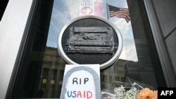 Sejumlah tanda penghormatan diletakkan di bawah logo USAID yang telah disegel di markas lembaga tersebut di Washington, DC, pada 7 Februari 2025. (Foto: AFP/Mandel Ngan)