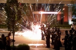 A firework explodes by a police line as demonstrators gather to protest the death of George Floyd, May 30, 2020, near the White House in Washington.