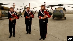 A Jordanian military band plays bagpipes and drums in front of UH-60A helicopters, better known as Black Hawks, delivered from the United States to Jordan's Marka Airport, in Amman, March 3, 2016. 