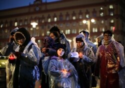 People hold candles as they gather at a monument outside the former KGB headquarters in Moscow, Russia, Oct. 29, 2019, in an annual commemoration of the victims of purges under Soviet dictator Joseph Stalin.
