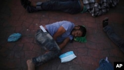 FILE - A migrant who returned from the U.S. the previous day sleeps outside a Mexican immigration office in Matamoros, Mexico, Aug. 4, 2019, on the border with the U.S.