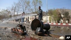 Afghan firefighters clean up the site of a deadly suicide bombing near Kabul University, in Kabul, March 21, 2018. 