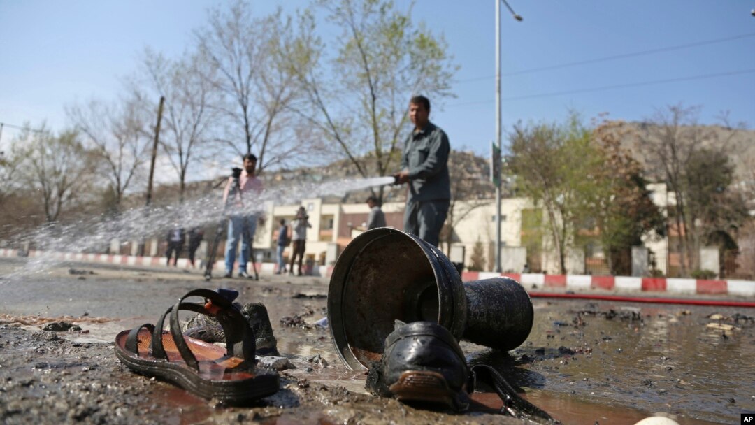 Afghan firefighters clean up the site of a deadly suicide bombing near Kabul University, in Kabul, March 21, 2018. 