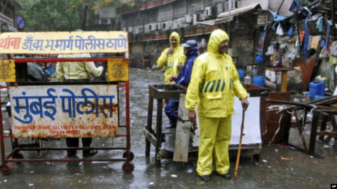 Policemen stand guard in the rain next to a barricade they installed at one of the sites of Wednesday's triple explosions, near the Opera House in Mumbai, July 14, 2011