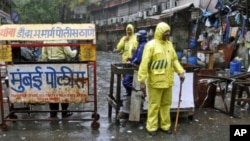 Policemen stand guard in the rain next to a barricade they installed at one of the sites of Wednesday's triple explosions, near the Opera House in Mumbai, July 14, 2011