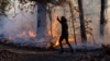 A morning jogger gestures as he runs past a fire lit by members of the New Jersey Forest Fire Service as part of back burning efforts alongside Palisades Interstate Parkway in Englewood Cliffs, New Jersey, Nov. 8, 2024. 