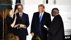 26일 백악관에서 도널드 트럼프(오른쪽 두번째) 미국 대통령이 지켜보는 가운데, 에이미 코니 배럿(왼쪽) 신임 대법관이 클래런스 토머스(오른쪽) 대법관 앞에서 선서하고 있다.
