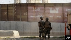 Marines look on during work to fortify the border structure that separates Tijuana, Mexico, behind, and San Diego, near the San Ysidro Port of Entry, Nov. 9, 2018, in San Diego, CA. 