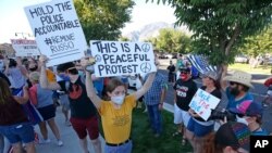 Protesters hold signs outside the Cottonwood Heights Police Department Aug. 3, 2020, in Cottonwood Heights, Utah, in response to use of force by officers at a protest the night before that resulted in the arrest of eight people.