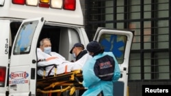 Petugas medis tengah menurunkan seorang pasien dari dalam ambulans di depan Rumah Sakit Elmhurst di Queens, New York, 24 April 2020. (foto: dok).