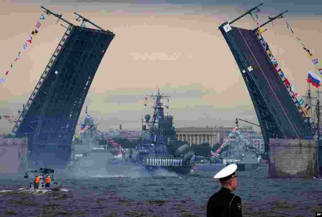 Warships float past the Dvortsovy (Palace) drawbridge rising above the Neva River during the Navy Day parade in St.Petersburg, Russia.
