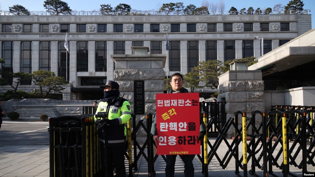 A man stands with a sign that reads "The constitutional court should immediately accept the impeachment of President Yoon Suk Yeol" in front of the constitutional court in Seoul, Dec. 16, 2024. 