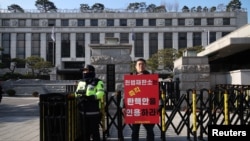 A man stands with a sign that reads "The constitutional court should immediately accept the impeachment of President Yoon Suk Yeol" in front of the constitutional court in Seoul, Dec. 16, 2024. 