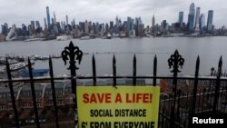 A sign in Hamilton Park in Weehawken, New Jersey, promotes social distancing April 3, 2020, with the New York City skyline in the background.