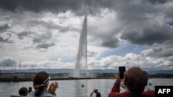 People applaud during a ceremony marking the restarting of Geneva's landmark fountain, known as Jet d'Eau, following the COVID-19 outbreak, June 11, 2020.