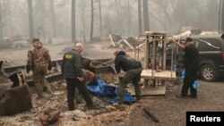 Para petugas mengevakuasi jenazah korban tewas akibat kebakaran hutan di Paradise, California. 