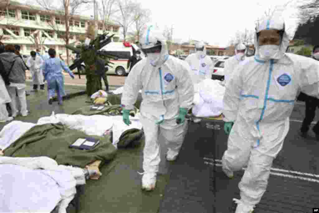 Futaba Kosei Hospital patients who might have been exposed to radiation are carried into the compound of Fukushima Gender Equality Center in Nihonmatsu in Fukushima Prefecture Sunday morning, March 13, 2011.