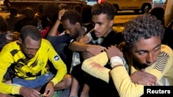 Migrants sit after they were detained by Libyan security forces in Tripoli, Libya, Oct. 8, 2021. 