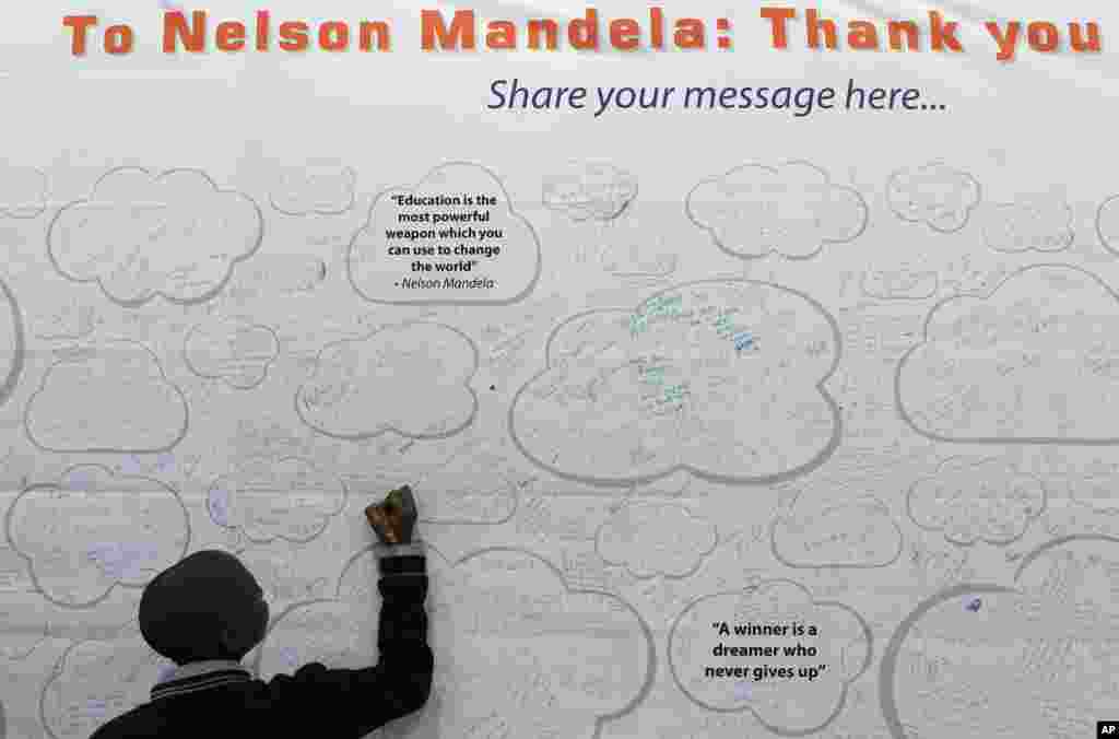 Thabiso Boya adds his get-well message on a poster for former South African President Nelson Mandela, at the Education Expo in Johannesburg, South Africa. Mandela remains in the hospital for the 13th day for a recurring lung infection. 