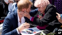 Britain's Prince Harry is embraced by 98-year-old Daphne Dunne during a walkabout outside the Opera House in Sydney, Australia, Oct. 16, 2018.