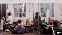 Pasien menerima perawatan di bawah tenda yang darurat di kompleks rumah sakit untuk menangani membludaknya pasien positif COVID-19, di Yogyakarta, 13 Juli 2021. (Agung Supriyanto / AFP)