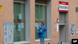 FILE - A man looks at notices on the window of an unemployment office in Madrid, Spain, April 28, 2020.