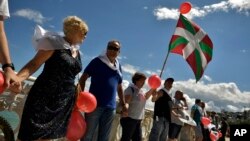 A man holds up a Basque flag, or Ikurrina, as people gather along La Concha beach to make a human chain calling for the independence of the Basque Country with the slogan ''Our Right to Decide'' or in Basque language, ''Gure Esku Dago,'' in the Basque city of San Sebastian, northern Spain, June 10, 2018. 