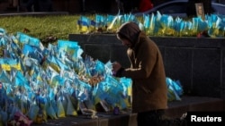 Un hombre visita un lugar conmemorativo improvisado que tiene banderas ucranianas con los nombres de los militares caídos, en la Plaza de la Independencia, en medio del ataque de Rusia a Ucrania, en Kiev, Ucrania, el 7 de noviembre de 2023.