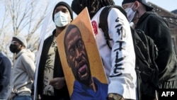 A man holds a portrait of George Floyd during a demonstration outside the governor's mansion on March 6, 2021, in St. Paul, Minnesota.