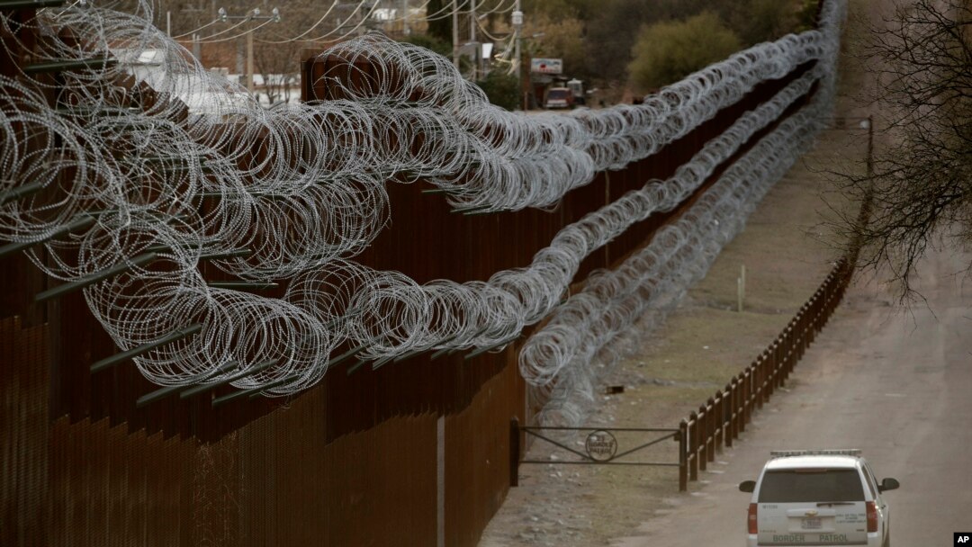 Para petugas patroli perbatasan AS berpatroli di sepanjang dinding perbatasan yang memisahkan Nogales, Meksiko, dari Nogales, Arizona, 2 Maret 2019.
