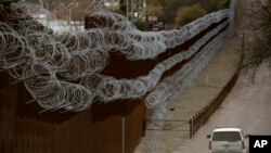 FILE - A Customs and Border Patrol agent patrols on the U.S. side of a razor-wire-covered border wall that separates Nogales, Mexico, from Nogales, Arizona, March 2, 2019.