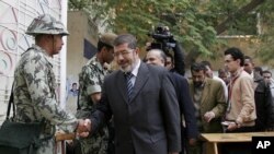 Muslim Brotherhood spokesman Mohammed Morsi shakes hands with a solider on the first day of parliamentary elections in Cairo, Egypt, Monday, Nov. 28, 2011.