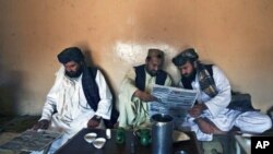 Pashtun men read local newspapers reporting the arrest of senior al Qaida leader Younis al- Mauritani at roadside tea shop in Quetta, Pakistan, September 6, 2011.
