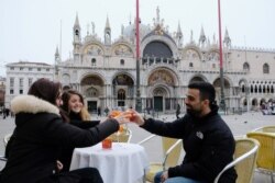Venetians drink an aperol spritz in the Caffe Lavena at St Mark's Square, which has begun offering a free drink with every drink ordered during the aperitivo hour to draw traffic amid the coronavirus outbreak, in Venice, Italy, March 5, 2020.