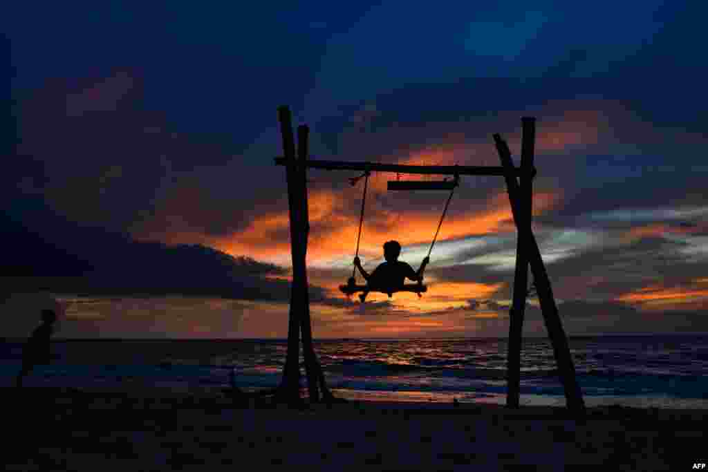 A child plays on a swing as the sun sets at Lhoknga beach in Aceh province, Indonesia.