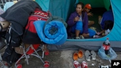 A migrant family waits in their tent on the street for buses to carry them to a new shelter, in Tijuana, Mexico, Dec. 1, 2018. Most of the thousands of migrants who had been camped out at the sports complex had agreed to move to the new, more distant shel