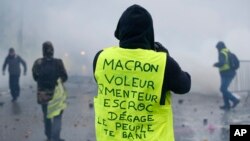 Seorang demonstran mengenakan jaket kuning bertuliskan “Macron, pencuri, pembohong, penjahat, pergi, warga mengusir Anda” dekat Champs-Elysees dalam unjuk rasa di Paris, Sabtu, 1 Desember 2018.