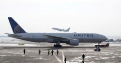 FILE - A United Airlines Boeing 777-200ER plane is towed as an American Airlines Boeing 737 plane departs from O'Hare International Airport in Chicago, Illinois, U.S., Nov. 30, 2018.