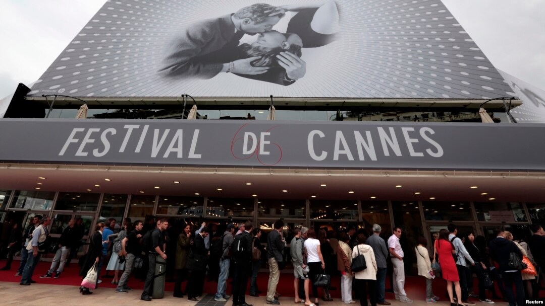 Para pengunjung antri untuk memasuki gedung "The Festival Palace" yang dihiasi poster raksasa Festival Film Cannes ke-66 di Cannes (15/5). Perhiasan senilai $1,4 juta yang akan dipinjamkan kepada para bintang Festival FIlm tersebut dikabarkan raib dari kamar hotel yang dihuni pegawai perempuan perusahaan perhiasan Swiss, Choppard.
