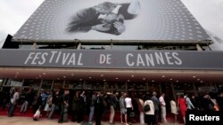 Para pengunjung antri untuk memasuki gedung "The Festival Palace" yang dihiasi poster raksasa Festival Film Cannes ke-66 di Cannes (15/5). Perhiasan senilai $1,4 juta yang akan dipinjamkan kepada para bintang Festival FIlm tersebut dikabarkan raib dari kamar hotel yang dihuni pegawai perempuan perusahaan perhiasan Swiss, Choppard.